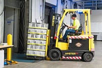 Fork lift driver unloading and loading goods from trailer to warehouse